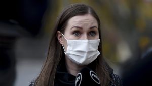 Sanna Marins regering ska i morgon onsdag diskutera möjligheten att utlysa undantagstillstånd som i våras. Mörkhårig kvinna i munskydd mot en brokig, diffus bakgrund. Statsminister Sanna Marin på väg till regeringens överläggning i Ständerhuset om coronaläget.