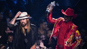 Lil Nas X:s låt Old town road vann titeln årets låt 2019 på MTV Video Music Awards. På låten hörs också Billy Ray Cyrus, pappa till sångerskorna Miley och Noah Cyrus. En svart man i en röd cowboyutstyrsel. I handen har han en vinststatyett. Brevid honom står en vit man i cowboyhatt och rockigt utseende.