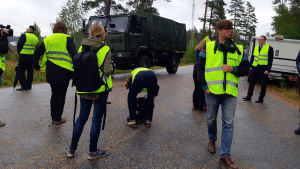 Under rättegångens första dag i måndags besökte tingsrätten olycksplatsen och gick igenom händelserna två år tidigare. Flera personer i gula västar på en asfalterad väg. I bakgrunden ett militärfordon och några andra bilar.