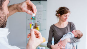 Enligt THL finns det risk för lokala epidemier på flera orter där många låter bli att vaccinera sina barn. En läkare förbereder vaccinationsspruta för en baby.
