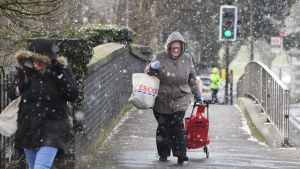 En kvinna vandrar genom den fallande snön i södra London. En kvinna vandrar genom snövädret i södra London.
