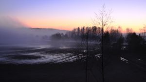 Aurinko nousee peltoaukeman takaa.