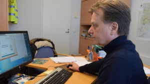 Raimo Parikka säger att man inte investerar annat än det man absolut måste de kommande åren. Raimo Parikka sitter vid datorn i sitt kontor.