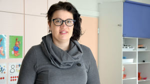 Annette Stelmachers barn har trivts i daghemmet Petter och själv trivs hon med att jobba där. En kvinna med mörkt hår, grå tröja och glasögon. Står inne i ett rum i ett daghem. Inga barn syns.