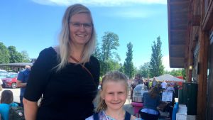 Jessica Karlsson och Ise Adamsson besökte potatisfestivalen i Nagu. Båda två älskar potatis. jessica karlsson står tillsammans med ise adamsson och ler mot kameran. hilmen är klarblå coh i bakgrunden syns festivalmänniskor.