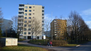 Om du skulle vara ett virus så skulle en bakterie vara som ett åtta våningar högt flervåningshus i jämförelse. Två barn går framför två höghus