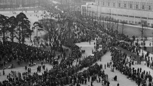 År 1945 var firandet i full gång igen. Här anländer första maj-tåget till vänsterförbundens gemensamma firande i Stadion. Ett svartvitt gammalt fotografi där man uppifrån ser en gata fylld av ett långt tåg av folk.