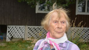 Anne Enberg följde intresserat med när lyftkransarmen grep tag om hennes båt och lyfte den ombord. Äldre kvinna med scarf runt halsen.
