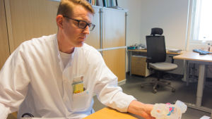 Juha Sinisalo verkar som professor i kardiologi. Här tittar han på en fysisk 3D-modell av ett hjärta. Juha Sinisalo