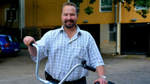 Werner Orre säger att staden gärna skulle se flera cykelvägar. En man i rutig skjorta står vid en cykel och ler.
