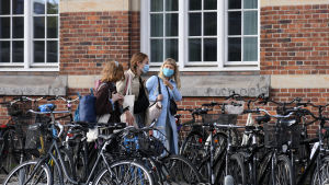 Coronasmittan sprider sig främst bland unga just nu. Ungdomar går på en gata med många parkerade cyklar. De bär munskydd.