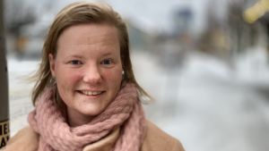 Sonja Jungar-Irjala. En kvinna med rosa halsduk står i en snöig stadsmiljö