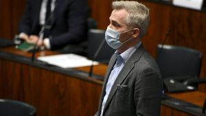Enligt uppgifter till Yle är SFP det regeringsparti som är mest motvilligt att införa begränsningar i rörelsefriheten. Gruppordförande Anders Adlercreutz säger att tröskeln för dylika restriktioner måste vara mycket hög. Anders Adlercreutz i munskydd står och talar i riksdagen.