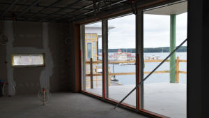 Bostäderna ligger ett stenkast från restaurang Knipan, den gula byggnaden på bilden. Foto taget i en bostad som hålls på att byggas. Genom glasdörrarna ser man stadsfjärden i Ekenäs och restaurang Knipan.