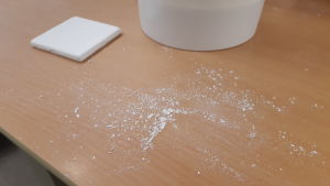 Den överflödiga glasyren sopas upp och kan användas på nytt. Damm från bortskrapad kakelglasyr.