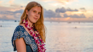 Au pair Annika seisoo ilta-auringossa rannalla lei kaulassaan.