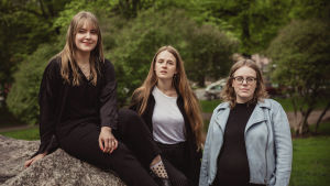 Malin Öhman, Kaneli Johansson och Jenna Matintupa är tre av fem medlemmar i Århundradets bokklubb. Tre av medlemmarna i årets jury för svenska yles litteraturpris poserar för kameran i en somrig park.