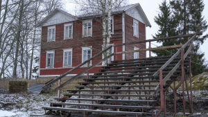 Läktaren som finns vid Wahlrooska stod förut vid Stundars i Solf. En gammal läktare framför ett gammalt rött hus.