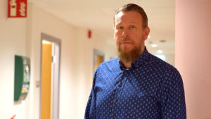 Stefan Fri, chef för sysselsättningstjänster i Raseborg, tror att sysselsättningsförsöket inneburit förbättringar. Man med skägg och i blå skjorta med prickar ser mot kameran.
