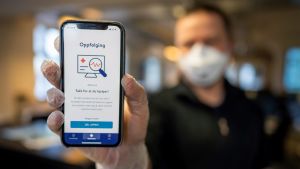Norge lanserade en coronavirusapp den 17 april. En man håller fram sin mobiltelefon. På mobilskärmen syns en coronavirusapp.