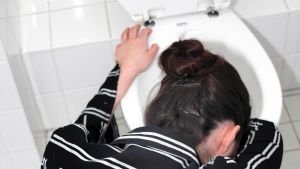 En kvinna böjer sig över en toalettskål.