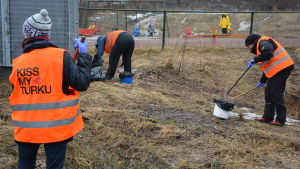 Flera frivilliga hundägare plockade skräp och hundbajs i Vilkkiläparken i Åbo. Tre kvinnor i orangea reflexvästar städar i en park.