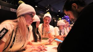 Slush skulle inte vara möjligt utan volontärerna. I år arbetade 2400 personer gratis för Slush. Vitklädda ungdomar vid en disk hjälper deltagare på Slush.