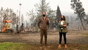 Harris (t.h.) har sagt att de förödande bränderna i Kalifornien är ett resultat av klimatförändringen. Här granskar hon ett brandhärjat samhälle tillsammans med Kaliforniens guvernör Gavin Newsom (t.v.). Senator Kamala Harris och guvernör Gavin Newsom står mitt i ett eldhärjat landskap med svarta munskydd på.