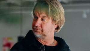 Saska Saarikoski tror att coronan har ändrat vår säkerhetskänsla liksom kriget gjorde för den äldre generationen 1939. Saska Saarikoski med pensel i handen målar en tavla med fundersam min.