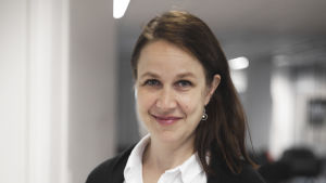 Veronika Honkasalo tycker inte att politikerna ska vara okritiska till tjänstemännen. En kvinna står i ett kontorslandskap. Hon ser in i kameran och ser glad ut. Hon är städigt klädd.