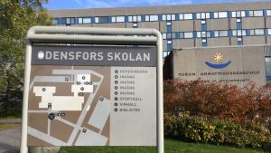 Åbo yrkeshögskolas tidigare utrymmen har fått fungera som kuliss för fiktiva Odensfors skolan. Skolskyltar utanför skolbyggnad.