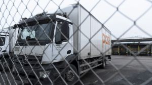 Lastbil med Postens logga står parkerad bakom ett stängsel.