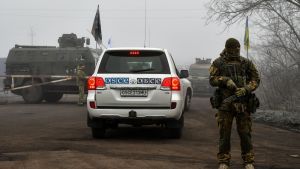 Ett OSSE-märkt fordon passerar en ukrainsk soldat på väg mot gränsposteringen Majorsk. OSSE övervakade fångutväxlingen. Ett OSSE-märkt fordon passerar en ukrainsk soldat på väg mot gränsposteringen Majorsk. OSSE övervakade fångutväxlingen.