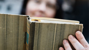 I texten kan vi förenas i ett här och nu, konstaterar författarna Taivassalo och Selensky. En gammal bok hålls i med en hand.