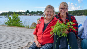 Atty Limnell och Johanna Lauramo tycker att utbudet på båten är bra. Två kvinnor sitter på en sten på en brygga.