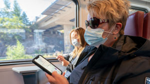 Coronablinkern kan till exempel meddela om exponeringar inom kollektivtrafiken. Koronavilkun käyttäjä lähijunassa.