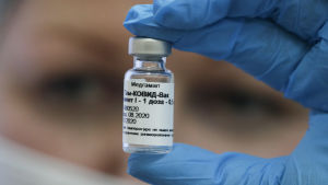 En person håller upp ett provrör med ryskt coronavaccin.