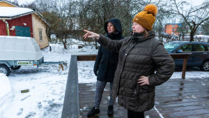 Birgitta Montulet och Kikke Heikkinen ser ut över kaninmarkerna på Jonasbacken. Kikke Heikkinen och Birgitta Montulet ser ut över en gårdsplan i snö.