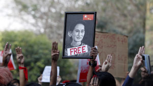 Demonstranter i Rangoon kräver att den fängslade regeringschefen Aung San Suu Kyi friges. Demonstranter håller tre fingrar i luften och bär på ett porträtt av den fängslade regeringschefen Aung San Suu Kyi.