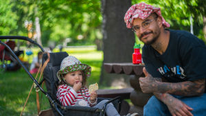 - Luncherna är fantastiska och vi kommer hit så gott som varje dag, säger Wille Mäkelä, som besökte parklunchen i lekparken Intia i Forsby i Helsingfors tillsammans med sin dotter Ansa på onsdagen. Wille Mäkelä sitter på en bänk och visar tummen upp. Hans dotter Ansa sitter i en barnvagn bredvid och äter en riskaka, med fundersam min.