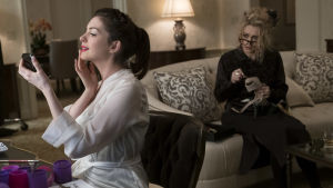Åh, vad jag är snygg tycker Daphne (Anne Hathaway) i soffan hennes designer Rose Weil (Helena Bonham Carter). Daphne (Anne Hathaway) sitter vid ett bord och beundrar sin spegelbild, Rose Weil (Helena Bonham Carter) sitter i en soffa längre bort och ser på.