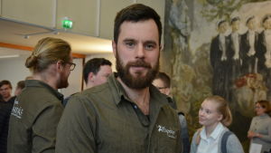 Linus Söderlund. Linus Söderlund i en mörkgrön skjorta i Kårens festsal, mycket folk runt omkring.