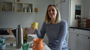 Jenny Paajes son grät varje dag under året efter första flytten. Kvinna med ljust hår och ljusblå klänning sittr vid ett vitt matbord och ler. I handen har hon en kaffemugg.