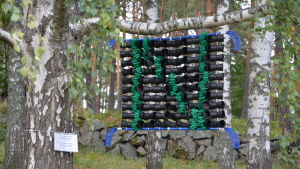 Vilken bokstav? En blå innebandyklubba, svarta blomkrukor och gröna plastremsor bildar ett konstverk. Bokstaven N.