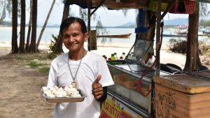 Vorasit Rattapong är beroende av den inhemska turismen. Han gör mer pengar genom att sälja köttbullar än när han var fiskare. En person står på en strand med en tallrik köttbullar.