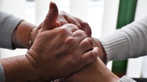 Hos den ideella föreningen Manden hjälper kvinnorna varandra med information, stöd och rättshjälp. Två par händer håller om varandra.