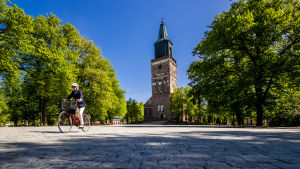 Uteserveringar planeras också intill Åbo domkyrka. En kvinna cyklar över domkyrkoskvären i Åbo.