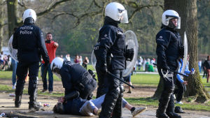 Poliser i kravallutrustning fick ta till hårda tag mot en del festivalbesökare. Polis i kravallutrustning, en polis håller en person på marken. Poliserna försöker skingra besökare på en fejkfestival i Bryssel.