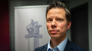 Överinspektör Mikko Cantell anser att spel med lootlådor liknar penningspel. Mikko Cantell från polisens lotteriförvaltning har på sig en kostym och tittar in i kameran. I bakgrunden syns polisens vapen.
