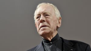 Max von Sydow läser "Mörkrets hjärta". Max von Sydow, en man i svart kostym och grått hår.